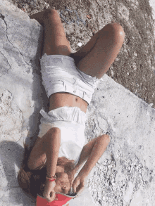 a woman in white shorts is laying on her back with her legs crossed