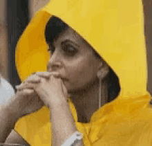 a woman wearing a yellow raincoat with a hood covering her face