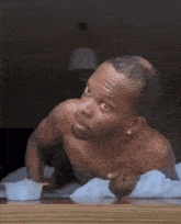a shirtless man is sitting at a table with a bowl of food on it .