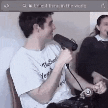 a man is holding a microphone while sitting in front of a woman .