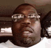 a close up of a man wearing glasses and a white shirt .