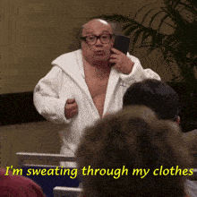 a man in a bathrobe is sweating through his clothes and talking on a cell phone