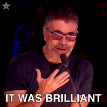 a man wearing sunglasses stands in front of a microphone with the words it was brilliant below him
