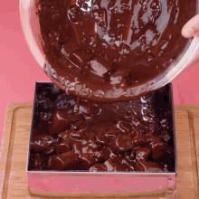 a person pouring chocolate sauce into a square pan