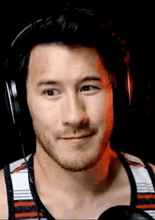 a close up of a man wearing headphones and a striped tank top .