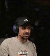 a man wearing a hat and headphones is laughing with his mouth open