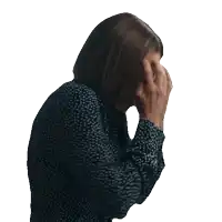 a woman wearing a black and white polka dot shirt is covering her face with her hands