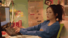 a woman is sitting at a desk with a computer and a keyboard .