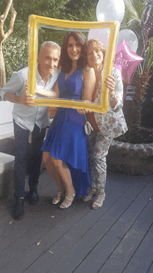 a woman in a blue dress is posing for a picture with her parents