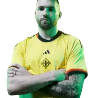 a man with his arms crossed wears a yellow shirt with a celtic cross on it