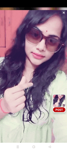 a woman wearing sunglasses and giving a thumbs up