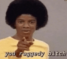 a man with an afro is pointing at the camera with his finger .