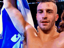 a shirtless man holds up a blue and white flag with the letter y on it