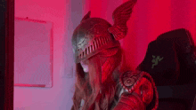 a woman wearing a helmet and armor is sitting in a chair in front of a computer .