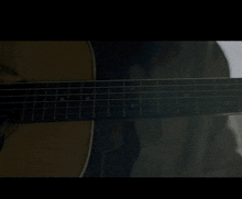a person is playing an acoustic guitar with a dark background