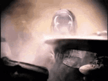 a man wearing a cowboy hat is standing in a foggy room .
