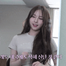 a woman in a white shirt is looking at her hair in front of a mirror with korean writing on it