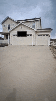 a house with three garage doors and a concrete driveway