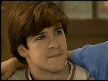 a close up of a man 's face with a woman 's arm around him