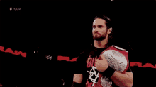 a wrestler is holding a world heavyweight championship belt in a ring .