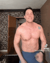 a shirtless man with a tattoo of a butterfly on his chest is dancing in front of a door