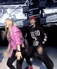 a man and a woman are dancing on a stage . the woman is wearing a pink shirt .