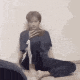 a man is sitting on the floor taking a picture of himself with a cell phone .