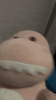 a pink stuffed animal with white teeth is laying on the floor .
