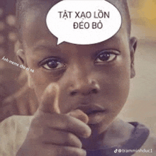 a young boy is pointing at the camera with a speech bubble above his head that says tạt xao lon deo bo