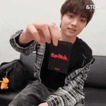 a young man in a plaid shirt is holding up a card that says ' gang blade ' on it