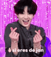 a young man is making a heart shape with his hands and the words si eres de jan written below him .