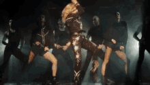 a group of women are dancing in a dark room in front of a bright light .