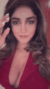 a woman in a red dress with a very plunging neckline is smiling and waving at the camera .