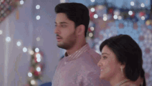 a man and a woman are standing next to each other and looking at something