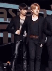a couple of men standing next to each other on a stage . one of the men is wearing a striped shirt .