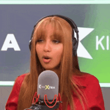a woman wearing headphones stands in front of a kiss extra microphone