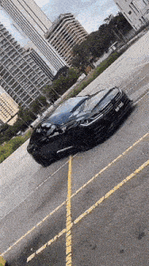 a black car is parked in a parking lot with buildings in the background .
