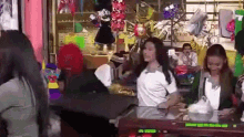 a group of people are sitting at a table in a store with balloons on display .