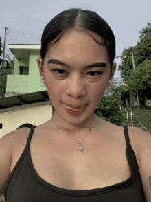 a woman wearing a black tank top and a necklace with a small star on it