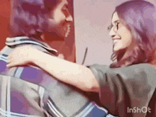 a man and a woman are hugging each other .