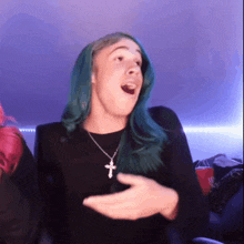 a person with green hair and a cross necklace making a funny face