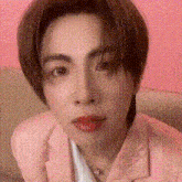 a close up of a person 's face wearing a pink jacket and necklace .