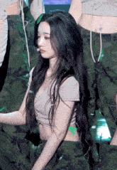a woman with long black hair is wearing a crop top