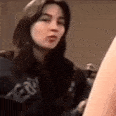a close up of a woman making a funny face while standing next to a person .