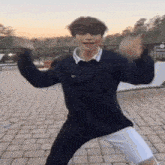 a young man wearing a black shirt and white shorts is dancing on a patio