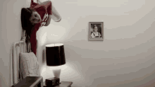 a woman in a red shirt is hanging upside down on a wall in a bedroom .