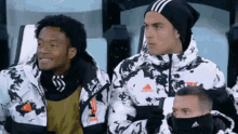 a group of soccer players wearing adidas jackets and hats