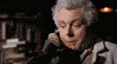 a man with white hair is talking on a telephone in a dark room .