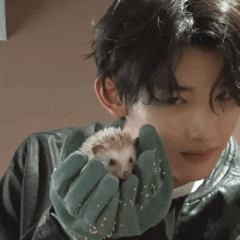 a man in a leather jacket is holding a small hedgehog