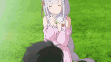 a girl in a pink dress is sitting in the grass looking at a boy